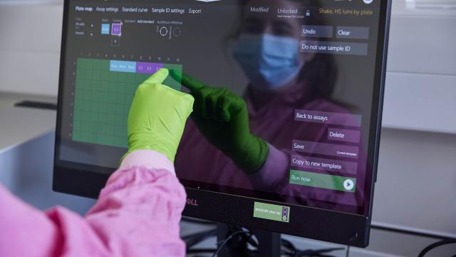 An arm with a green glove points to a computer screen