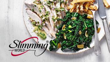 A white plate with strips of roasted chicken with a light drizzle of dressing, a side of cooked shredded greens and celeriac fries