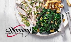 A white plate with strips of roasted chicken with a light drizzle of dressing, a side of cooked shredded greens and celeriac fries